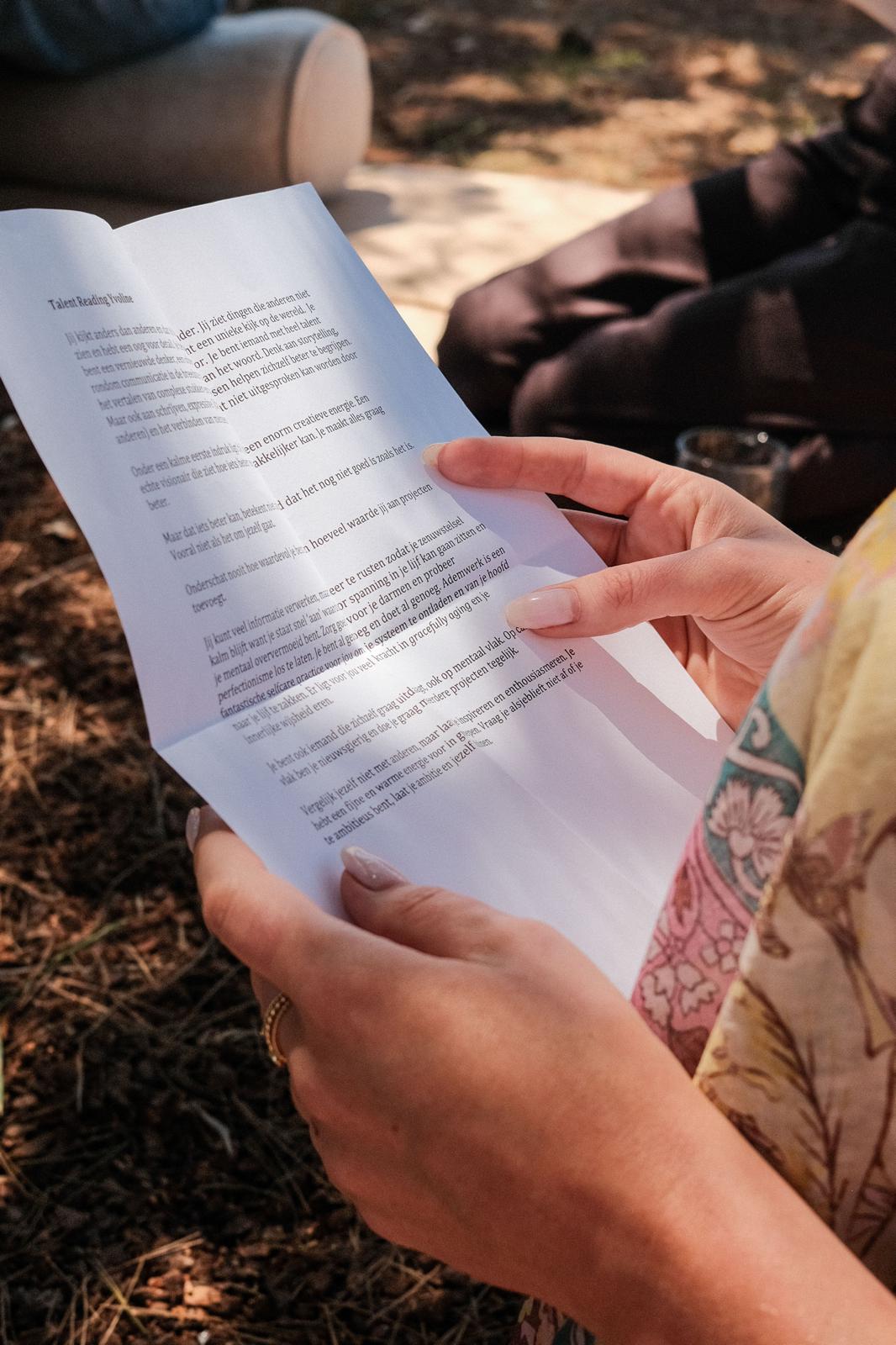 Handen houden de uitgeschreven persoonlijke reading vast in warm zonlicht